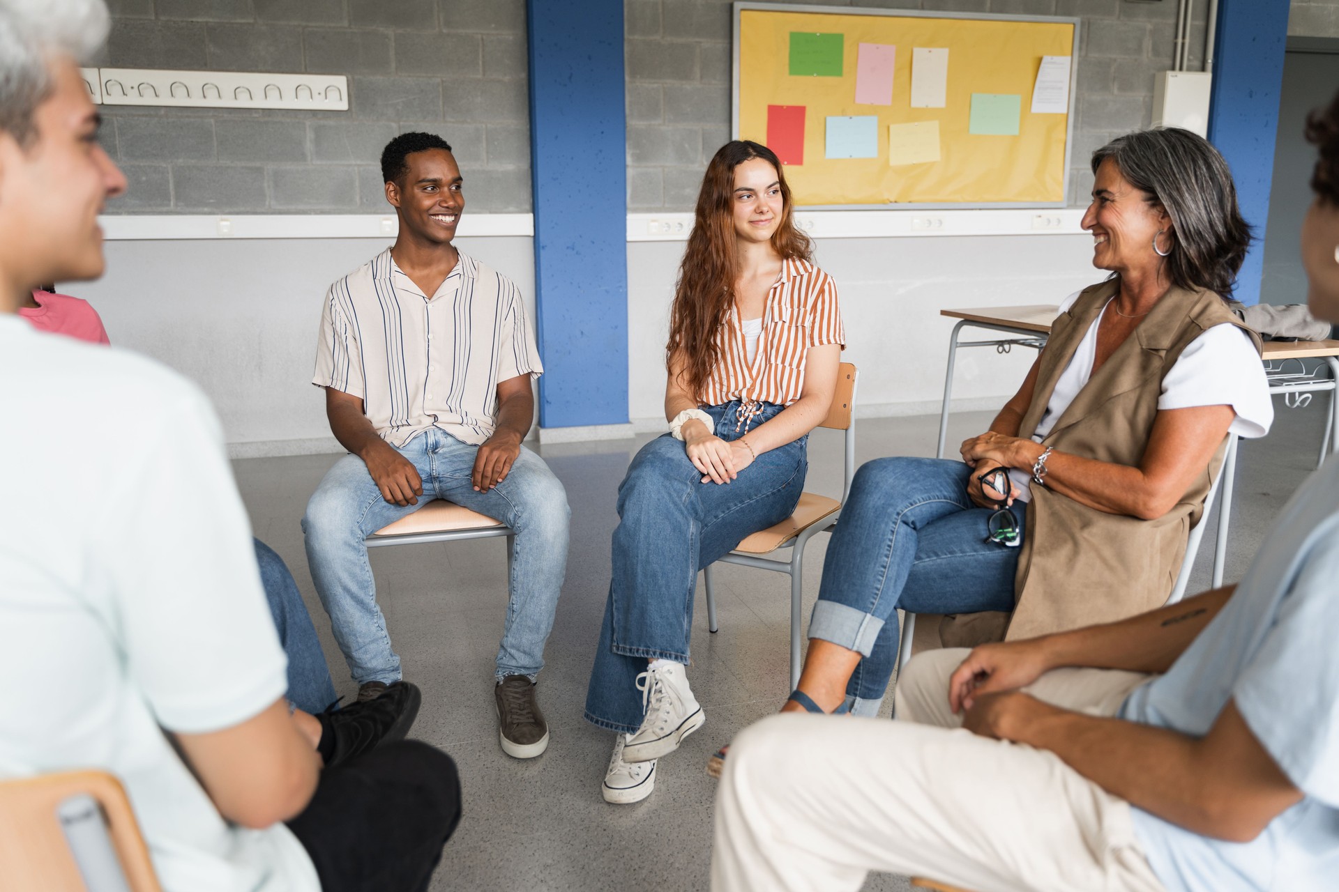 Mature female teacher listening and talking with teenager students - Group support discussion at College
