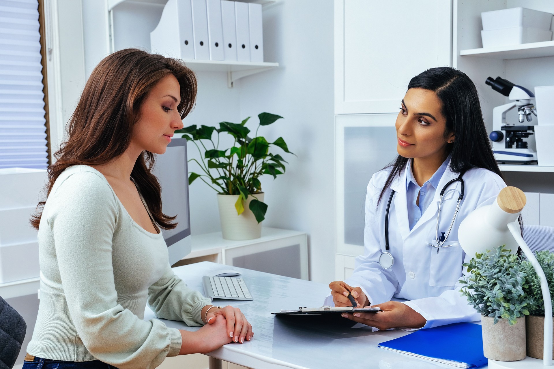 Young lady client patient visiting pleasant attentive female doctor physician at modern clinic medical center